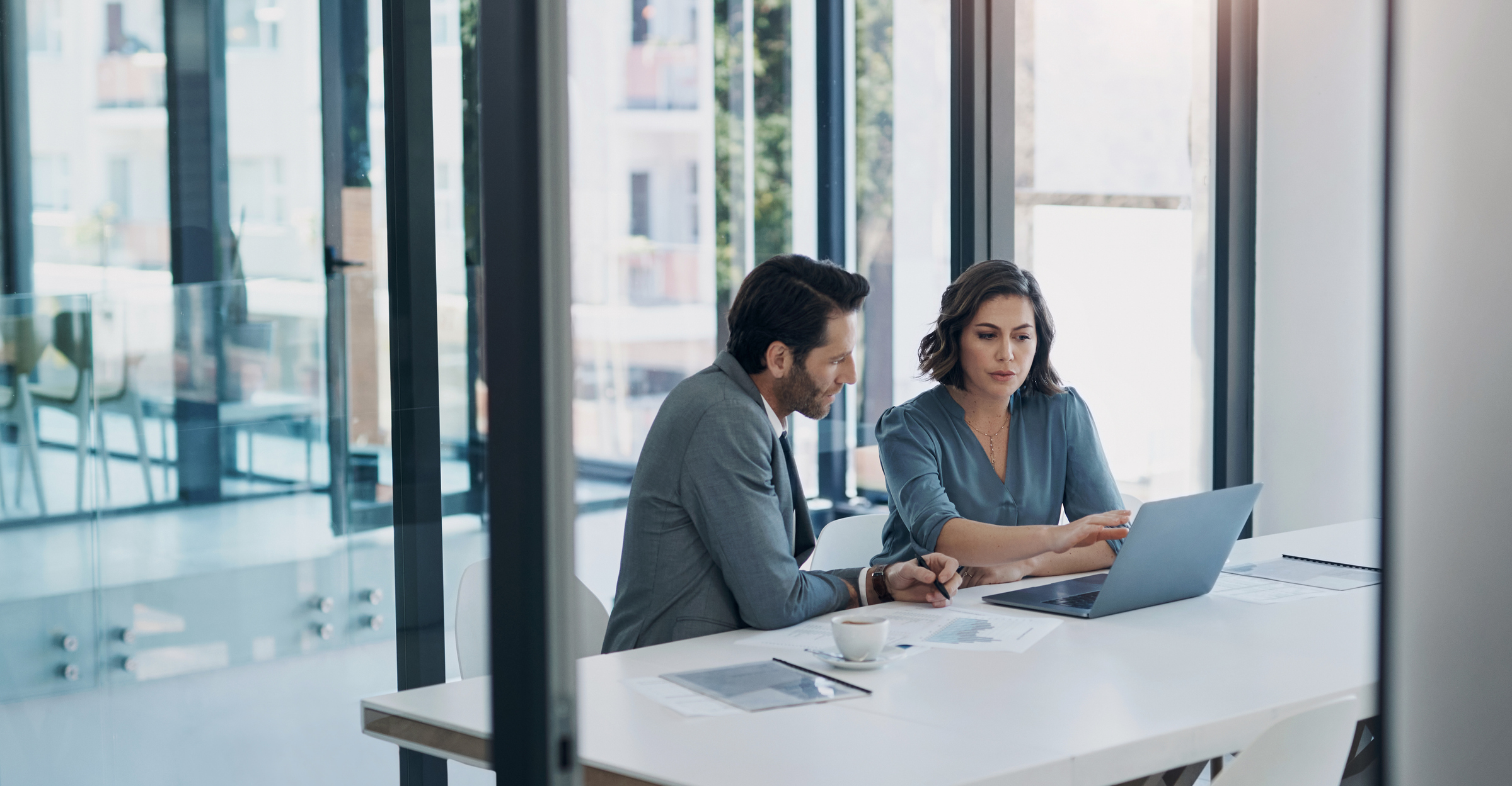 Business man, woman and laptop in discussion in team, brainstorming or proposal for b2b collaboration. People, computer or meeting with paperwork for financial strategy, idea or negotiation in office